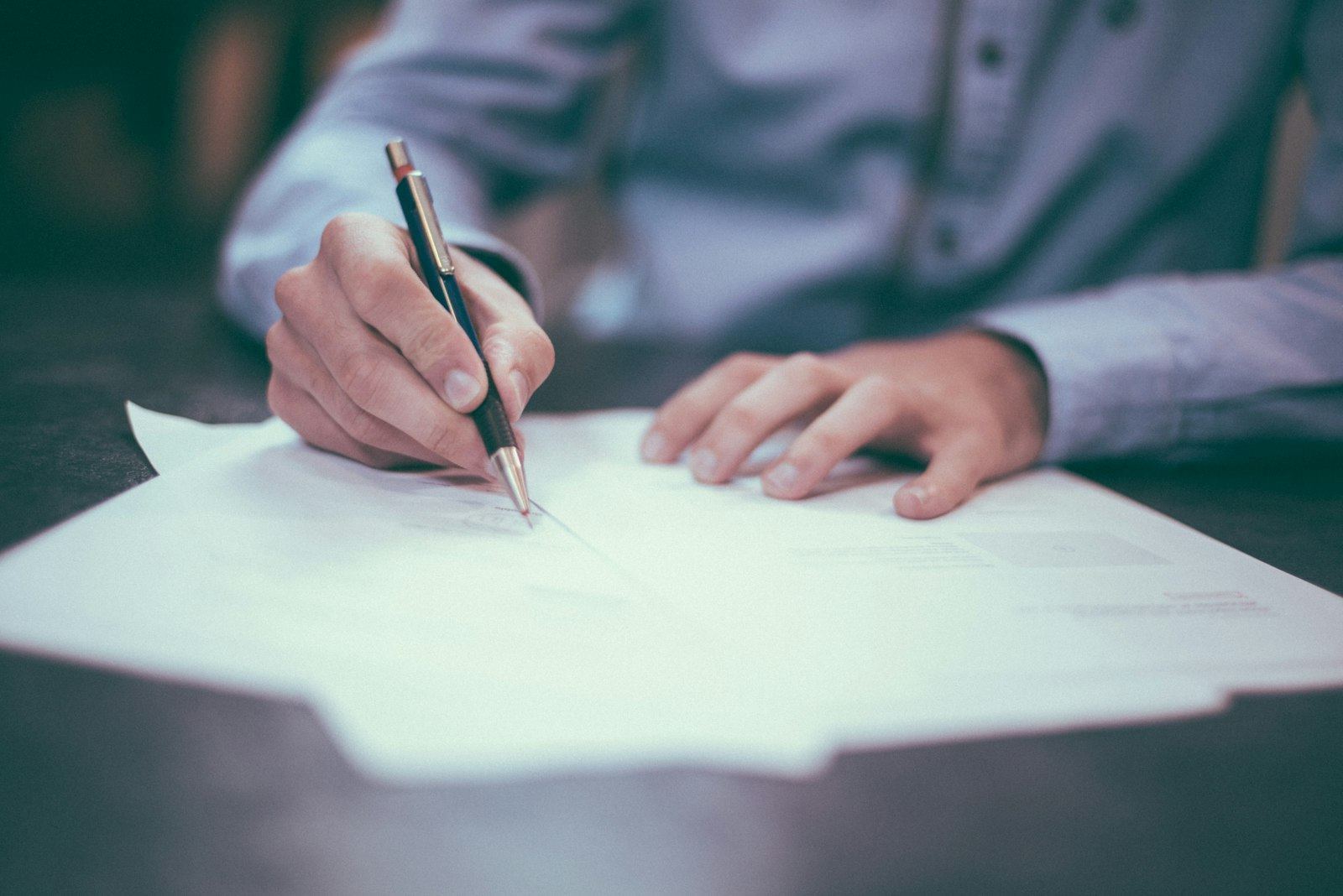 Hand signing permit paperwork at a desk